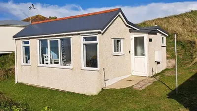 a small house with a white door on a hill at B14 Amulree, Riviere Towans in Hayle