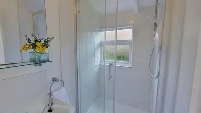 a bathroom with a shower with a sink and a window at B14 Amulree, Riviere Towans in Hayle