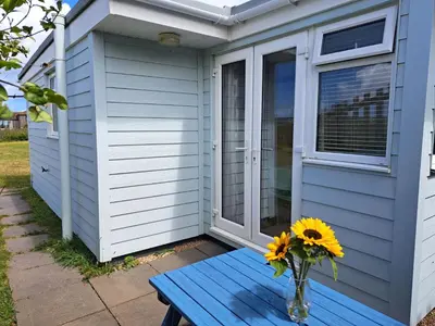 a vase of sunflowers on a blue table next to a house at A02 Mermaids Nest A2, Riviere Towans in Hayle