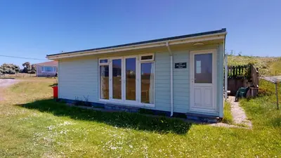 a small shed with a door in the grass at A02 Mermaids Nest A2, Riviere Towans in Hayle