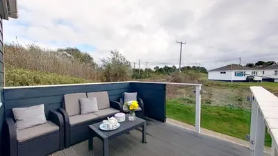 a patio with a couch and a table on a deck at A06 Rushdune A6, Riviere Towans in Hayle