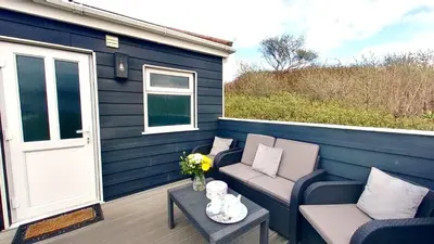 a patio with two chairs and a table and a door at A06 Rushdune A6, Riviere Towans in Hayle