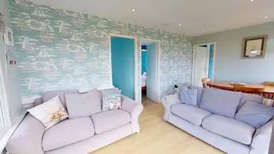 a living room with two couches and a wall mural at A06 Rushdune A6, Riviere Towans in Hayle
