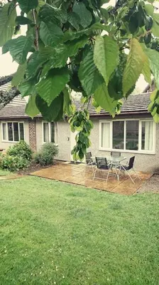 a house with a patio with two chairs and a table at Bungalow 62,North Cornwall, St. Tudy in Saint Tudy