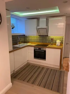 a kitchen with white cabinets and a black appliance at Homely Beachside Apartment in Newquay Town Centre! in Newquay