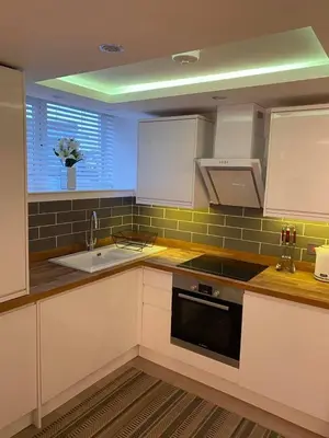 a kitchen with white cabinets and a sink and a window at Homely Beachside Apartment in Newquay Town Centre! in Newquay