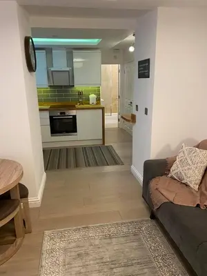 a living room with a couch and a kitchen at Homely Beachside Apartment in Newquay Town Centre! in Newquay