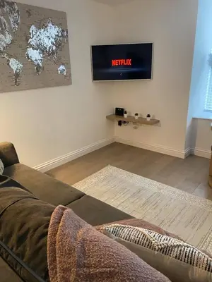 a living room with a couch and a clock on the wall at Homely Beachside Apartment in Newquay Town Centre! in Newquay