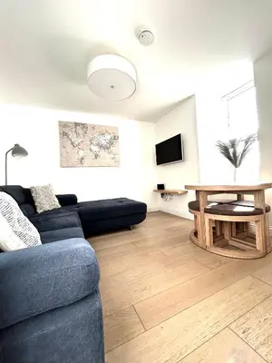 a living room with a blue couch and a table at Homely Beachside Apartment in Newquay Town Centre! in Newquay