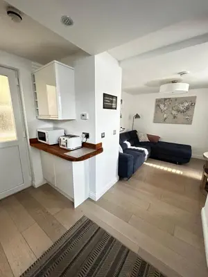 a living room with a blue couch and a kitchen at Homely Beachside Apartment in Newquay Town Centre! in Newquay
