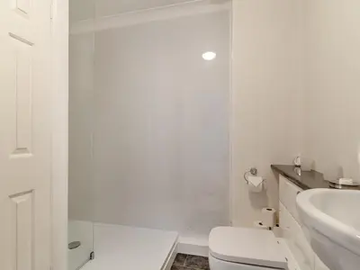 a white bathroom with a toilet and a sink at Seascape in Porthleven
