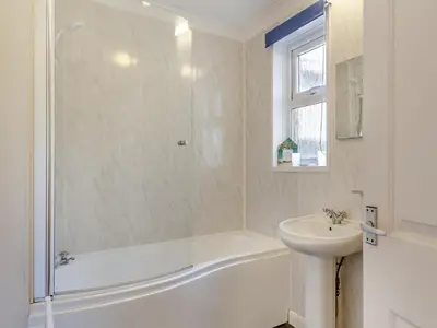 a white bathroom with a tub and a sink at Seascape in Porthleven