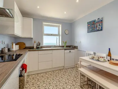 a kitchen with white cabinets and a window at Seascape in Porthleven