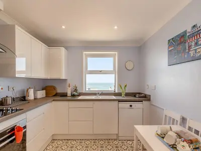 a white kitchen with a sink and a window at Seascape in Porthleven