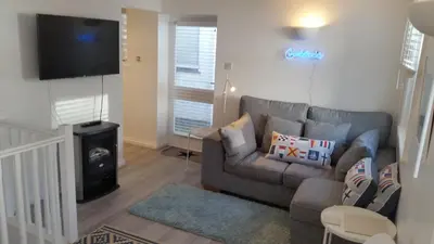 a living room with a couch and a flat screen tv at The Picture House Stylish Apartment in Fowey in Fowey