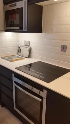 a kitchen counter with a stove and a microwave at The Picture House Stylish Apartment in Fowey in Fowey