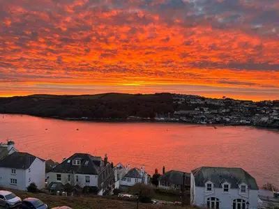 a sunset over a large body of water with houses at Bracken's Retreat in Lostwithiel