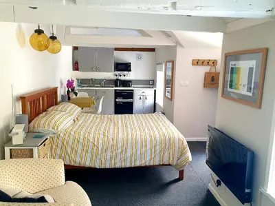 a living room with a bed and a kitchen at Bracken's Retreat in Lostwithiel