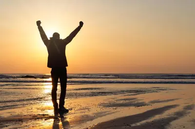 a man standing on the beach with his arms in the air at Stylish Central Famouth Studio with Parking | WiFi | in Falmouth