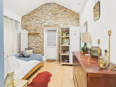 a room with a bed and a stone wall at Stylish Central Famouth Studio with Parking | WiFi | in Falmouth