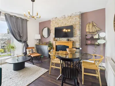 a living room with a table and chairs and a fireplace at Central Falmouth Flat with Free Parking in Falmouth