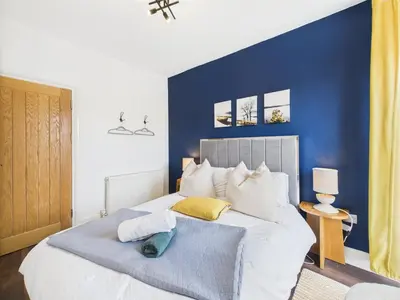 a bedroom with a blue accent wall and a bed at Central Falmouth Flat with Free Parking in Falmouth