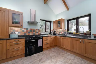 a large kitchen with wooden cabinets and black appliances at Trevelyan in St Ives