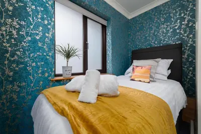 a bedroom with a large bed with blue wallpaper at Trevelyan in St Ives