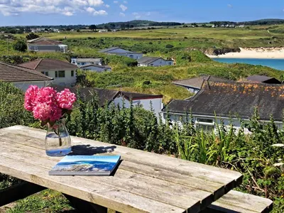 a vase of flowers and a book on a wooden table at B44 Sea Urchin, Riviere Towans in Hayle