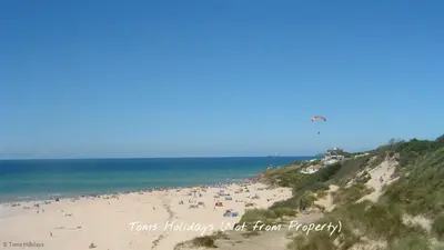 a group of people on a beach flying a kite at B44 Sea Urchin, Riviere Towans in Hayle