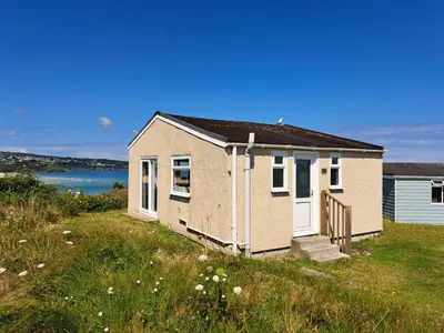 a small house on top of a grass field at B44 Sea Urchin, Riviere Towans in Hayle