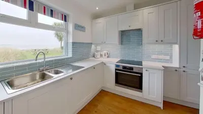 a kitchen with white cabinets and a sink and a window at B45 Phillippa, Riviere Towans in Hayle