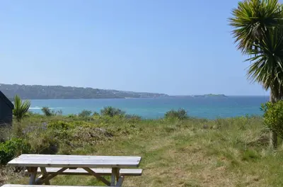 a picnic table sitting on a hill near the ocean at B45 Phillippa, Riviere Towans in Hayle