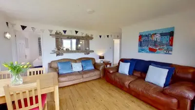 a living room with a leather couch and a table at B45 Phillippa, Riviere Towans in Hayle