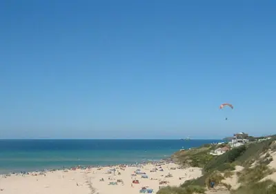 a group of people on a beach flying a kite at B51 Blue Bay, Riviere Towans in Hayle