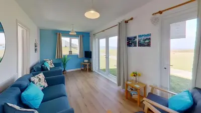 a living room with a blue couch and blue walls at B50 Kingfisher, Riviere Towans in Hayle