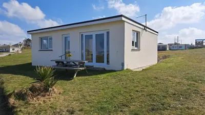 a small house with a picnic table in a field at B50 Kingfisher, Riviere Towans in Hayle