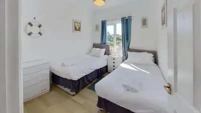two beds in a room with white walls at C15 Seamore, Riviere Towans in Hayle