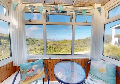 a room with windows and a table and chairs at C15 Seamore, Riviere Towans in Hayle