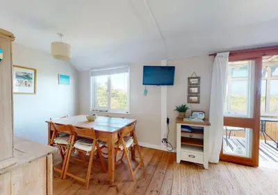 a dining room with a wooden table and chairs at C15 Seamore, Riviere Towans in Hayle