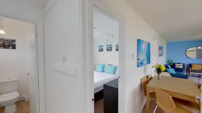 a white room with a bed and a table and a bathroom at B52 Oyster, Riviere Towans in Hayle