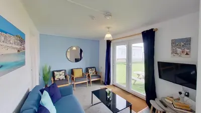 a living room with a blue couch and a large window at B52 Oyster, Riviere Towans in Hayle