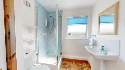 a white bathroom with a shower and a sink at C23 Wilmar, Riviere Towans in Hayle