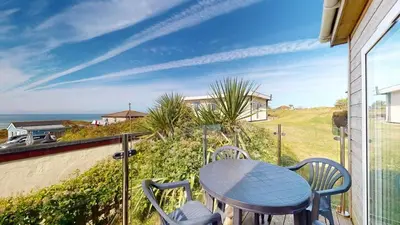 a table and chairs on a balcony with a view of the ocean at C23 Wilmar, Riviere Towans in Hayle