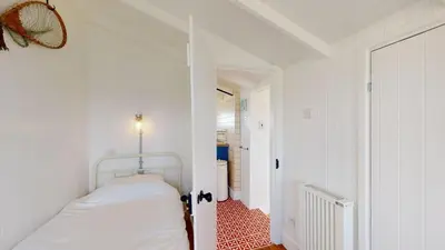 a white bedroom with a bed and a hallway at C24 Rosemary, Riviere Towans in Hayle