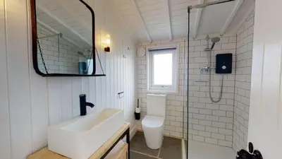 a bathroom with a toilet and a sink and a mirror at C24 Rosemary, Riviere Towans in Hayle