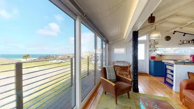 a room with a balcony with a view of the ocean at C24 Rosemary, Riviere Towans in Hayle