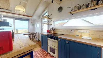 a kitchen with blue cabinets and a large window at C24 Rosemary, Riviere Towans in Hayle