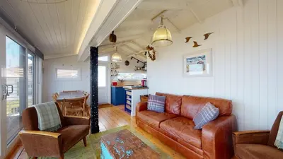 a living room with a leather couch and chairs at C24 Rosemary, Riviere Towans in Hayle