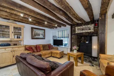 a living room with a couch and a tv at Lantau Cottage: Historic Elizabethan house very close to the beach in Looe